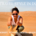 Woman joyfully jumping in the desert with blue sky background, wearing green joggers and white tank top, enjoying Dubai adventure