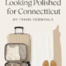 Flat lay of stylish summer travel essentials including toiletry bag, sandals, dress, and packing cubes for a family trip to Connecticut, featured on Polished and real lifestyle blog.